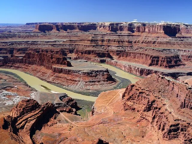 Una vista ampia di un fiume che serpeggia attraverso un profondo canyon di roccia rossa a strati