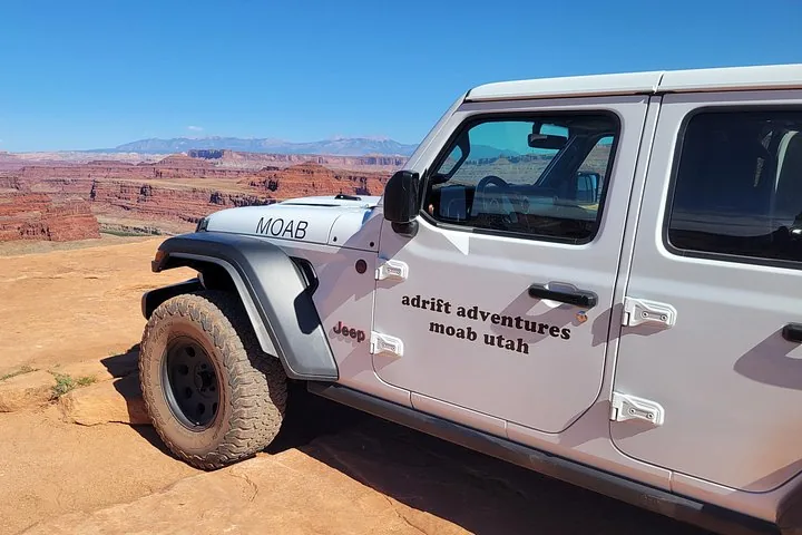 Gros plan sur une Jeep de tourisme blanche stationnée avec vue sur un canyon
