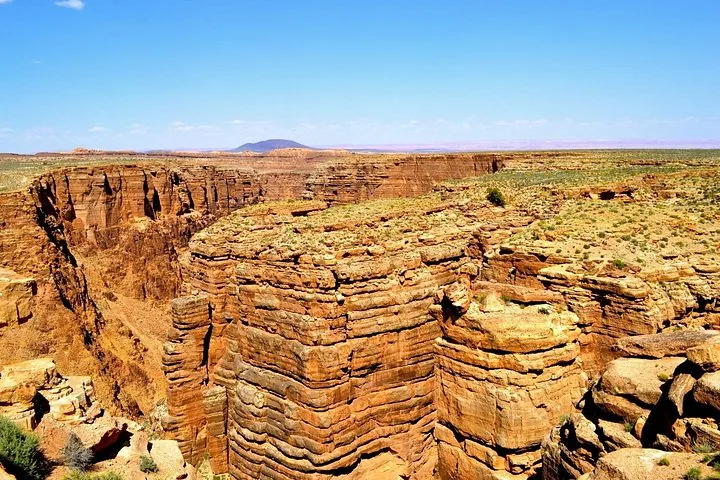 Deep canyons carved into layered red rock under a clear blue sky