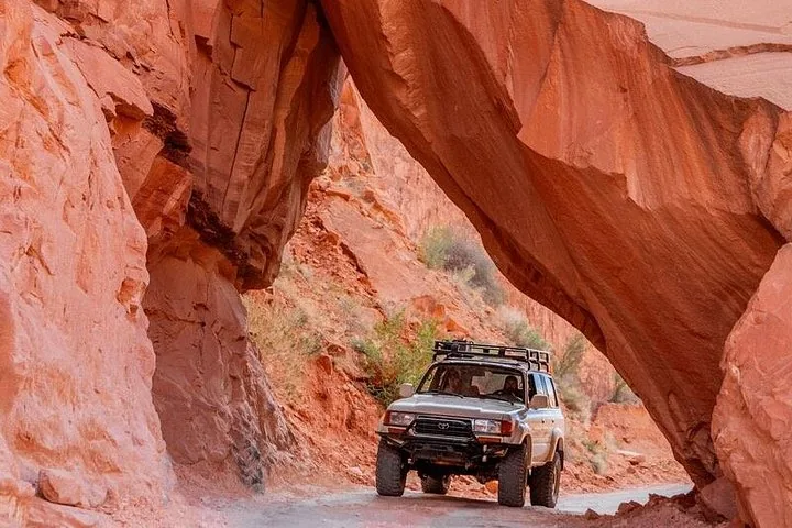 Ein 4x4-Fahrzeug fährt durch einen engen Felsbogen in einem Canyon