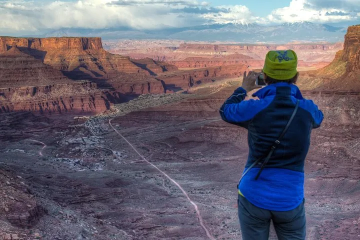 Eine Person fotografiert von einem Aussichtspunkt aus eine weite Canyonlandschaft