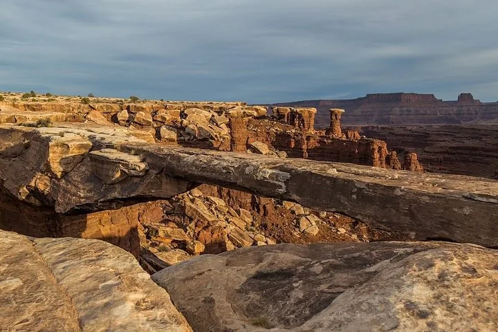 Ein Natursteinbogen überspannt eine Kluft am Rand eines Canyons